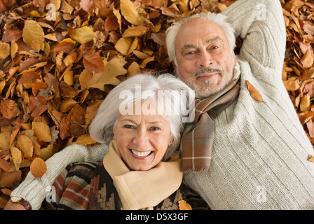 Older couple laying in autumn leaves Stock Photo