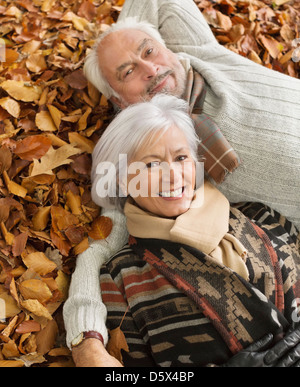 Older couple laying in autumn leaves Stock Photo