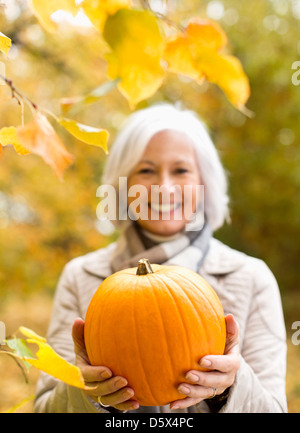 Older woman holding pumpkin in park Stock Photo