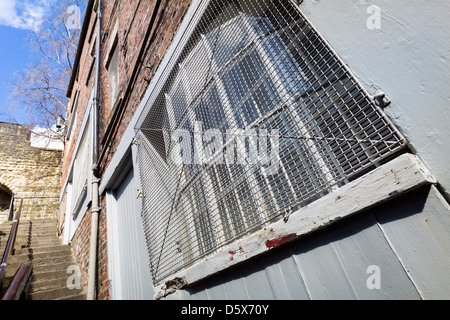 Old building with a wire mesh guard to protect the window Stock Photo