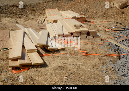 piles of lumber laying on the ground by a construction site Stock Photo