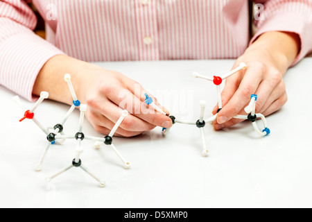 Hand of female student assembling amino acid molecule models for science project Stock Photo