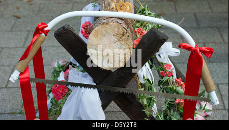 A saw hangs on a sawhorse holding a trunk of wood that the newly-weds have just sawed through after their wedding ceremony in Sieversdorf, Germany, 01 September 2012. Photo: Patrick Pleul Stock Photo