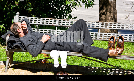 Middle aged businessman having a siesta sleep rest snooze nap on park seat bench Seville Andalusia Andalucia Spain Europe Stock Photo