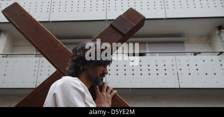 An amateur actor wearing a crown of thorns portraying Jesus carries a cross in Stuttgart-Bad Cannstatt, Germany, 06 April 2012. The Italian Catholic Parish San Martino simulated the Passion of Christ with a Good Friday Procession this year. Photo: MARIJAN MURAT Stock Photo