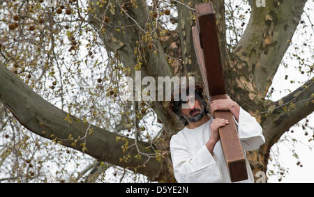 An amateur actor wearing a crown of thorns portraying Jesus carries a cross in Stuttgart-Bad Cannstatt, Germany, 06 April 2012. The Italian Catholic Parish San Martino simulated the Passion of Christ with a Good Friday Procession this year. Photo: MARIJAN MURAT Stock Photo