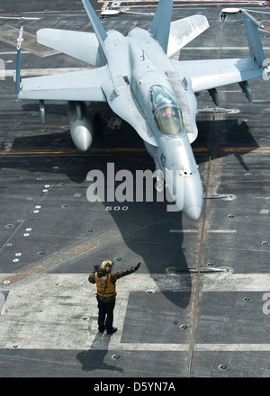 US Navy Sailors signals to a Marine Corps F/A-18C Hornet aircraft on the flight deck of the aircraft carrier USS Nimitz April 4, 2013 in the Pacific Ocean. Stock Photo