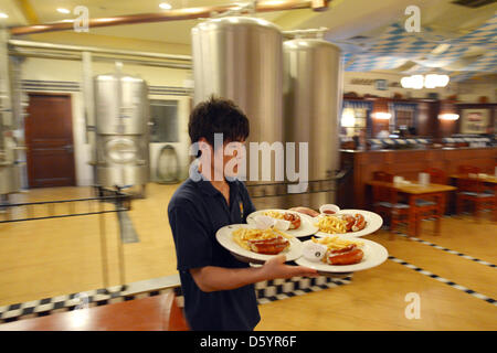 A man serves french fries and bratwurst at the restaurant and bar 'Paulander Munich' located in a hotel in Shenyang, China, 13 October 2012. Photo: Rainer Jensen Stock Photo