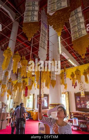 Chiang Mai, Thailand. April 10, 2013. A woman makes merit ahead of Songkran by giving an offering at Wat Phra Singh in Chiang Mai. Songkran is celebrated in Thailand as the traditional New Year's Day from 13 to 16 April. Songkran is in the hottest time of the year in Thailand, at the end of the dry season and provides an excuse for people to cool off in friendly water fights that take place throughout the country. The traditional Thai New Year has been a national holiday since 1940, when Thailand moved the first day of the year to January 1. Credit: Zuma/Alamy Live News Stock Photo