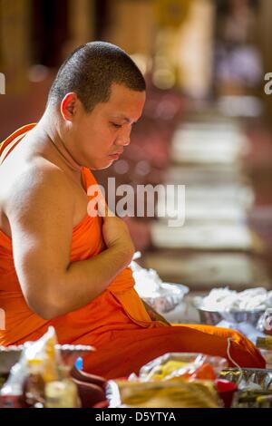 Chiang Mai, Thailand. April 10, 2013. A monk meditates before Songkran at Wat Phra Singh in Chiang Mai. Songkran is celebrated in Thailand as the traditional New Year's Day from 13 to 16 April. Songkran is in the hottest time of the year in Thailand, at the end of the dry season and provides an excuse for people to cool off in friendly water fights that take place throughout the country. The traditional Thai New Year has been a national holiday since 1940, when Thailand moved the first day of the year to January 1. The first day of the holiday period is generally the most devout Stock Photo