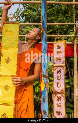 Chiang Mai, Thailand. April 10, 2013. A monk hangs prayer flags for Songrkran in Wat Phan Tao in Chiang Mai. Songkran is celebrated in Thailand as the traditional New Year's Day from 13 to 16 April. The date of the festival was originally set by astrological calculation, but it is now fixed. Songkran is in the hottest time of the year in Thailand, at the end of the dry season, and provides an excuse for people to cool off in friendly water fights that take place throughout the country. The traditional Thai New Year has been a national holiday since 1940. Credit: Zuma/Alamy Live News Stock Photo