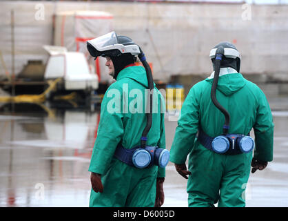 Two workers wearing full protective suits and helmets walk towards burnt out container ship MSC Flaminia in Wilhelmshaven, Germany, 07 November 2012. The wrecked ship has been moored at JadeWeserPort since September after an explosion set it on fire in July. Photo: INGO WAGNER Stock Photo