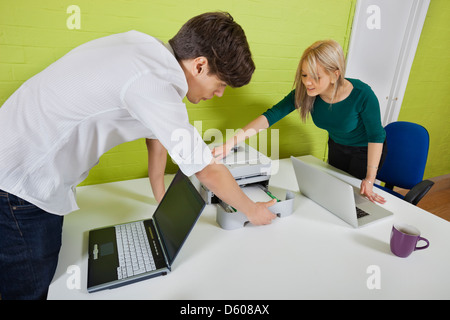 Young businesspeople setting up printer with laptops t desk Stock Photo