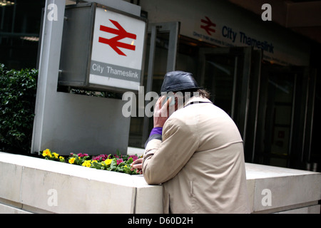 Man on a mobile telephone outside a train station in London Stock Photo