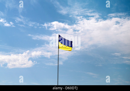 Flag of Ukraine with flag pole waving in the wind on front of blue sky Stock Photo