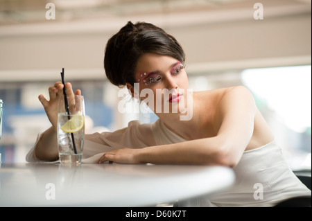 A beautiful young woman teenage girl with 1960's style hair, clothes and makeup, big eyelashes, in a bar UK Stock Photo