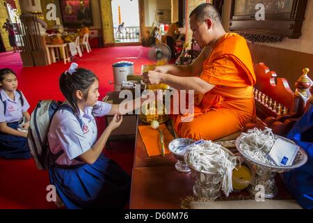 April 10, 2013 - Chiang Mai, Thailand - A monk ties a string bracelet on a schoolgirl's wrist after she made a Songkran offering at Wat Phra Singh in Chiang Mai. Songkran is celebrated in Thailand as the traditional New Year's Day from 13 to 16 April. (Credit Image: © Jack Kurtz/ZUMAPRESS.com) Stock Photo