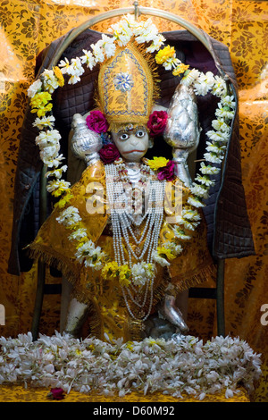 Offerings of flowers adorn a figurine of the Hindu deity Hanuman at a shrine in Udaipur, Rajasthan, India Stock Photo