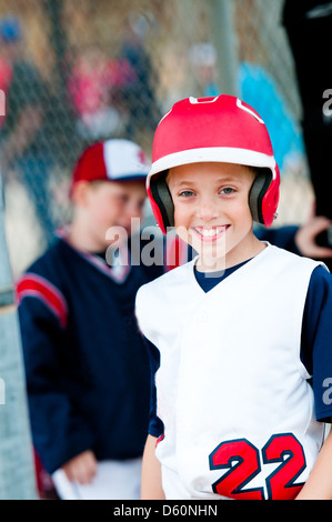Little league baseball boy with helmet in dugout smiling. Stock Photo