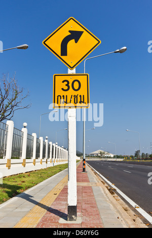 Road Sign warns Drivers to Limit Speed Ahead Dangerous Curve. Stock Photo