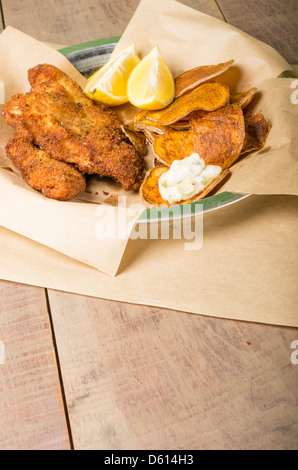 Fried fish and chips with lemon on a wooden table Stock Photo