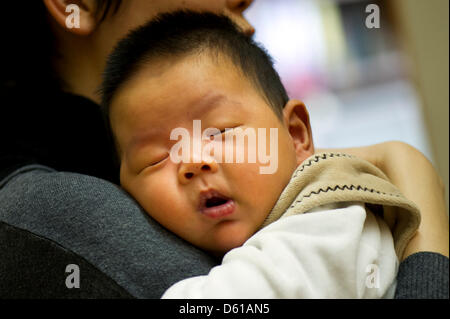 Baby boy 'Frei' arrives with his parents for a meeting with the mayor at the city hall in Freiberg, Germany, 12 April 2012. Two months after his birth 'Frei' met his honorary godfather and mayor of Freiberg. His Chinese parents live in Freiberg and signed the city's 'silver book'. Frei's parents declared their love for their new home town by naming their first son 'Frei' which in C Stock Photo