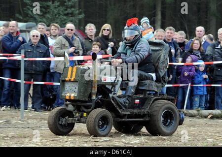 A participant races on his lawn mower past by-standing spectators during the Lawn mower fun race in Aukrug-Homfeld, Germany, 14 April 2012. Around a dozen teams took part in the fun race with their converted lawn mowers which featured lawn mower engines of up to 120 hp achieving a speed of around 100 km/h. Photo: Carsten Rehder Stock Photo