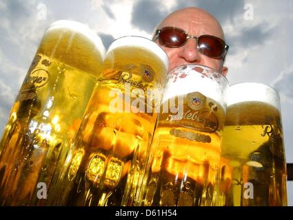 (file) - A dpa file picture dated 22 April 2012 shows a man carrying full beer steins in Potsdam, Germany. German Beer prices have risen by 9.6 percent since 2005. Photo: Ralf Hirschberger Stock Photo