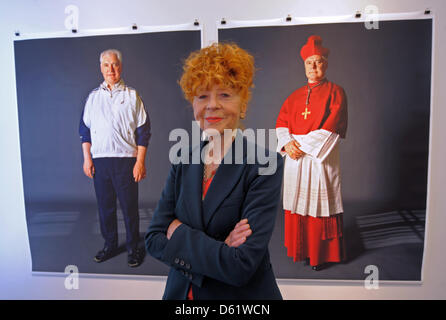 Photographer Herlinde Koelbl poses in front of two photos of Bishop Gerhard Ludwig Mueller at her new exhibition 'Kleider machen Leute' ('Clothes make the man') in Dresden, Germany, 03 May 2012. Koelbl's exhibition at the German Hygiene Museum Dresden showing people in casual and professional clothing is open until 29 July 2012.  Photo: MATTHIAS HIEKEL Stock Photo