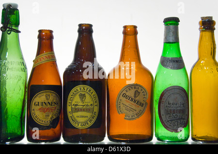Horizontal close up of a row of different coloured old glass Guiness bottles. Stock Photo