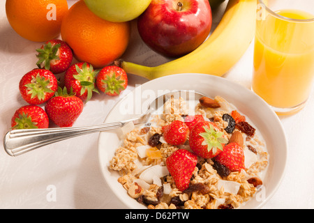 Bowl of cereal, fruits and orange juice on tabletop - breakfast. Stock Photo