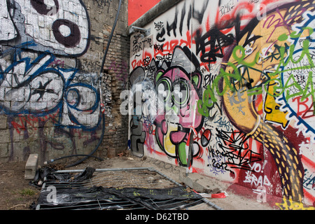 Where young Germans once risked their lives, graffiti and tags now adorn the concrete surfaces of original sections of the Berlin wall at the East Side Gallery on Muhlenstrasse, Berlin. The site is the former border between Communist East and West Berlin during the Cold War. The Berlin Wall was a barrier constructed by the German Democratic Republic (GDR, East Germany) starting on 13 August 1961, that completely cut off (by land) West Berlin from surrounding East Germany and from East Berlin .. (More in Description). Stock Photo