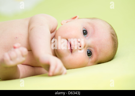 baby girl lying on her side over green background Stock Photo