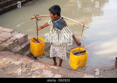 Young boy carrying a pannier filled with water, Minnanthu, Bagan, Myanmar, (Burma) Stock Photo