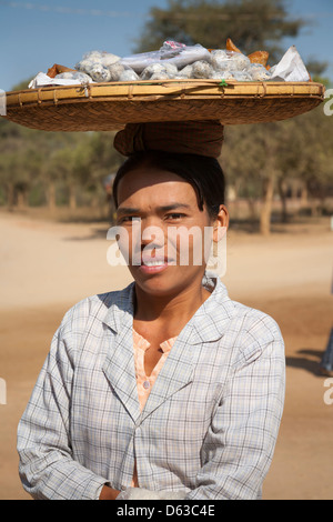 Woman carrying basket of food on her head, Bagan, Myanmar, (Burma) Stock Photo