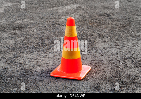 Red and yellow striped warning cone on asphalt road Stock Photo