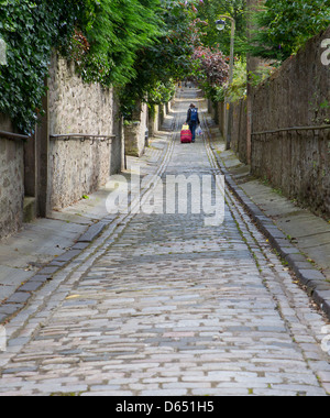 person walking down straight cobbled lane Stock Photo