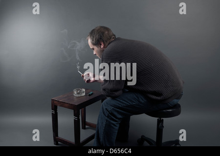 A young caucasion man is alone, stressed, got fired from work is unemployed and sad. Stock Photo