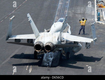 A US Navy plane director guides an F/A-18C Hornet onto a catapult for take off on the flight deck of aircraft carrier USS Dwight D. Eisenhower April 9, 201 in the North Arabian Sea. Stock Photo