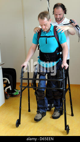 Physiotherapists have affixed walking robot EKSO on the legs of a paraplegic at Rehaklinik in Potsdam, Germany, 13 June 2012. With the help of the walking robot, paraplegics can stand on their own two feet again. Photo: Bernd Settnik Stock Photo