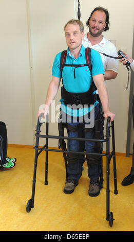 Physiotherapists have affixed walking robot EKSO on the legs of a paraplegic at Rehaklinik in Potsdam, Germany, 13 June 2012. With the help of the walking robot, paraplegics can stand on their own two feet again. Photo: Bernd Settnik Stock Photo