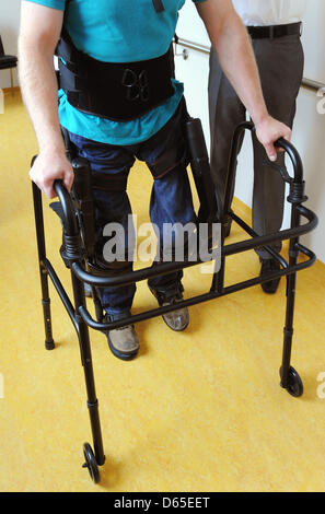 Physiotherapists have affixed walking robot EKSO on the legs of a paraplegic at Rehaklinik in Potsdam, Germany, 13 June 2012. With the help of the walking robot, paraplegics can stand on their own two feet again. Photo: Bernd Settnik Stock Photo