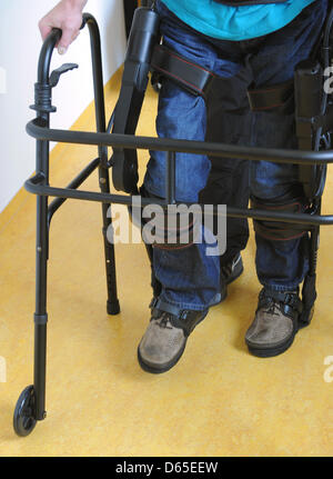 Physiotherapists have affixed walking robot EKSO on the legs of a paraplegic at Rehaklinik in Potsdam, Germany, 13 June 2012. With the help of the walking robot, paraplegics can stand on their own two feet again. Photo: Bernd Settnik Stock Photo