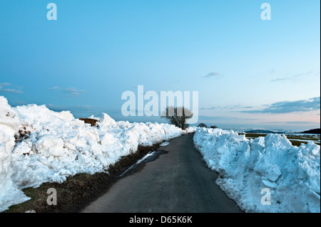 Snowdrifts on the summit of Stonewall Hill, nr Knighton, Powys, UK, in the late winter of 2013. The lane follows the border between England and Wales Stock Photo