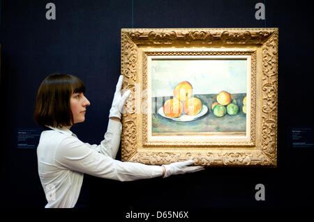 London, UK. 12th April 2013. A Sotheby's employee poses in front of Paul Cezanne 'Les Pommes 1889-1890'  (Est. $25-35 million). The work will go on sale at Sotheby’s New York in May 2013. The Blockbuster sales at include works by Richter, Modigliani, Picasso, Rodin, Bacon, Cezanne. Credit: Piero Cruciatti / Alamy Live News Stock Photo