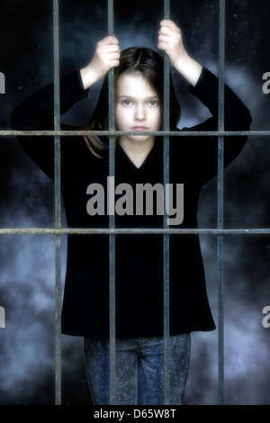 a girl imprisioned behind a grate Stock Photo