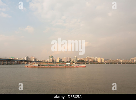 A river boat on Han river in Seoul, South Korea, during the golden hour. Seen from the Yeouido island. Stock Photo