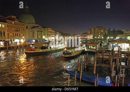 Vaporetti or water buses next to the pontoon or stop at Ferrovia station on the Grand Canal at night Venice Italy Stock Photo