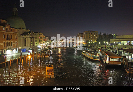 Vaporetti or water buses next to the pontoon or stop at Ferrovia station on the Grand Canal at night Venice Italy Stock Photo