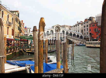 Blue covered gondolas for the winter in front of the Rialto Bridge with wooden mooring posts Venice Italy Stock Photo